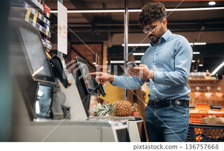 By cash register. Man is in the grocery store 136757668