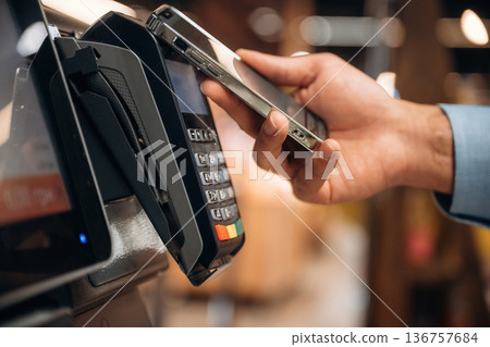 Wireless transfer. Close up view of man customer that is paying for products by credit card in grocery store Wireless transfer. Close up view of man customer that is paying for products by credit card in grocery store 136757684