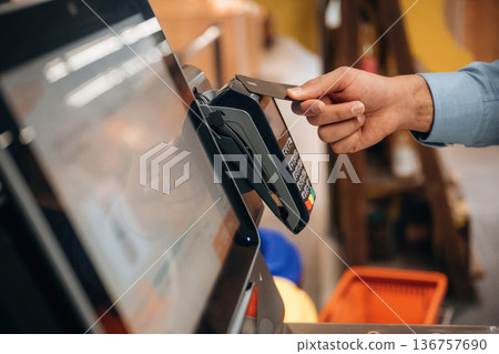 Close up view of man customer that is paying for products by credit card in grocery store Close up view of man customer that is paying for products by credit card in grocery store 136757690