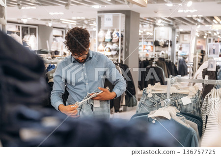 Blue jeans. Man customer is in the clothing store 136757725