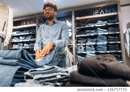 Shelves are behind. Man customer is in the clothing store Shelves are behind. Man customer is in the clothing store 136757735
