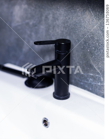 Sleek faucet closeup. Closeup of matte black fixture with reflective water droplet Sleek faucet closeup. Closeup of matte black fixture with reflective water droplet 136758069