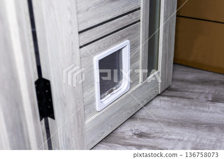 Weathered door with pet access. Chipped painted door with pet entry and aged wooden floor Weathered door with pet access. Chipped painted door with pet entry and aged wooden floor 136758073
