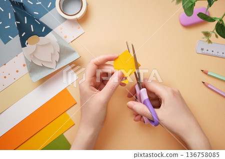 Hands cut duck out of yellow paper. Eraser, scissors, pencil on beige background. DIY handmade project for children. Hands cut duck out of yellow paper. Eraser, scissors, pencil on beige background. DIY handmade project for children. 136758085