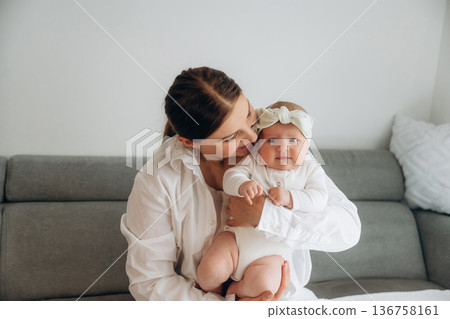 On the gray sofa. Woman is with her little toddler baby daughter 136758161
