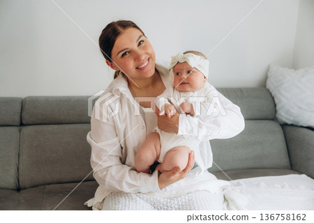 On the gray sofa. Woman is with her little toddler baby daughter 136758162