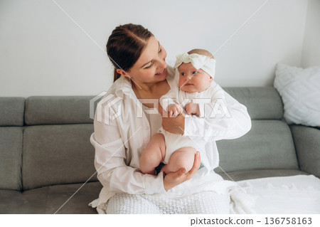On the gray sofa. Woman is with her little toddler baby daughter 136758163
