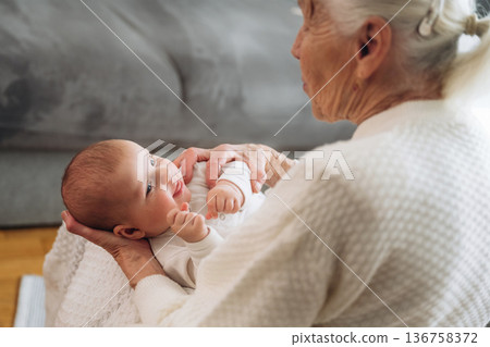 View from behind, holding toddler in hands. Grandmother with cute toddler baby at home 136758372