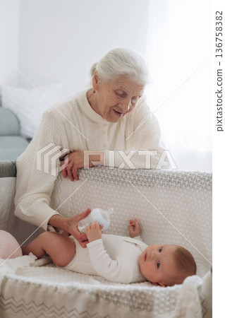 Taking care of toddler that is lying down. Grandmother with cute toddler baby at home 136758382