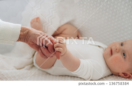 Senior woman is holding hands with little baby Senior woman is holding hands with little baby 136758384