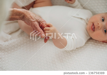 Two people. Senior woman is holding hands with little baby 136758389