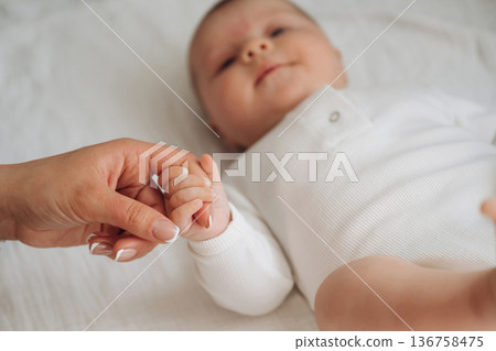 Love and care conception. Close up view of mother and little baby holding hands 136758475