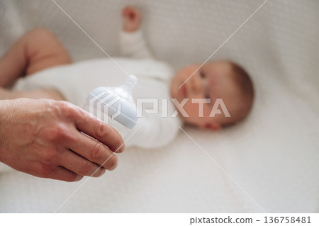 Holding bottle. Close up view of mother and little baby Holding bottle. Close up view of mother and little baby 136758481