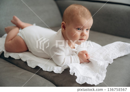 Lying down. Cute little baby is on the sofa Lying down. Cute little baby is on the sofa 136758567