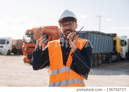 Conversation by using walkie talkie. Male worker is near truck outdoors 136758737