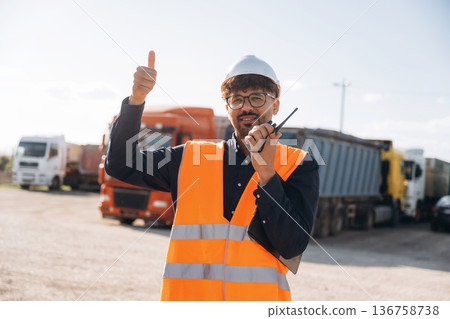 Conversation by using walkie talkie. Male worker is near truck outdoors Conversation by using walkie talkie. Male worker is near truck outdoors 136758738