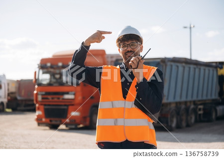Conversation by using walkie talkie. Male worker is near truck outdoors Conversation by using walkie talkie. Male worker is near truck outdoors 136758739