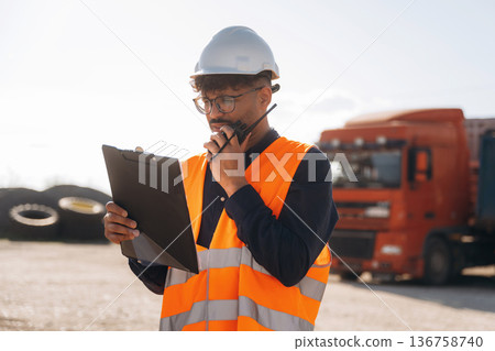 Conversation by using walkie talkie. Male worker is near truck outdoors 136758740