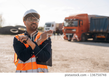 Gestures with hands. Male worker is near truck outdoors Gestures with hands. Male worker is near truck outdoors 136758748