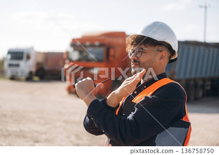Gestures with hands. Male worker is near truck outdoors 136758750