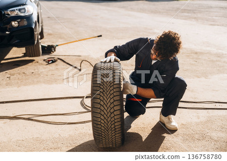 Checking the tire. Mechanic is with the car outdoors Checking the tire. Mechanic is with the car outdoors 136758780