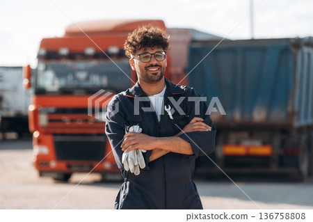 Arms crossed, standing. Male worker is near truck outdoors 136758808