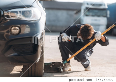 Ready to change the tire. Mechanic is with the car outdoors 136758809