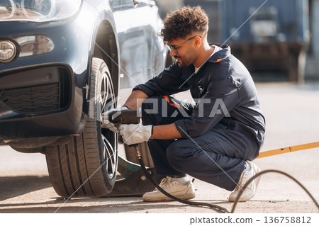 Process of changing the tire. Mechanic is with the car outdoors 136758812