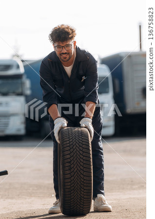 Brand new tire. Male worker is near truck outdoors Brand new tire. Male worker is near truck outdoors 136758823
