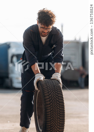 Brand new tire. Male worker is near truck outdoors Brand new tire. Male worker is near truck outdoors 136758824