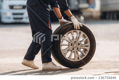 Side view. Man mechanic is with new tire Side view. Man mechanic is with new tire 136758846