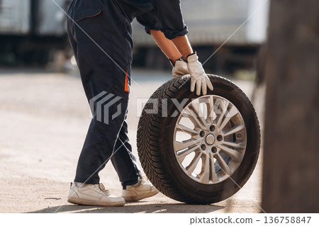 Side view. Man mechanic is with new tire 136758847
