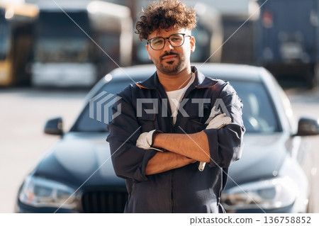 Posing, with arms crossed. Mechanic is with the car outdoors Posing, with arms crossed. Mechanic is with the car outdoors 136758852