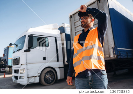 In orange uniform. Male worker is near truck outdoors 136758885