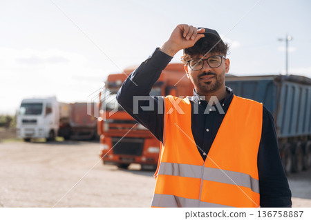 In orange uniform. Male worker is near truck outdoors 136758887