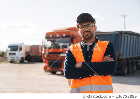 In orange uniform. Male worker is near truck outdoors In orange uniform. Male worker is near truck outdoors 136758889