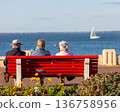 people sitting on a bench looking at the sea 136758956