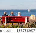 people sitting on a bench looking at the sea 136758957