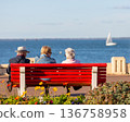 people sitting on a bench looking at the sea 136758958