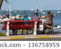 people sitting on a bench looking at the sea 136758959