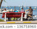 people sitting on a bench looking at the sea 136758960