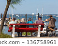 people sitting on a bench looking at the sea 136758961