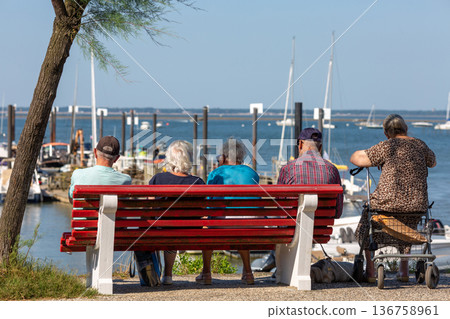 people sitting on a bench looking at the sea 136758961