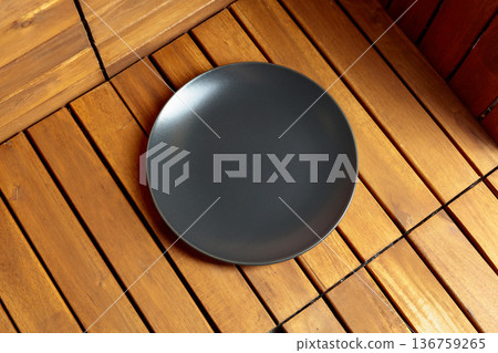 Empty black plate on natural wooden background. 136759265