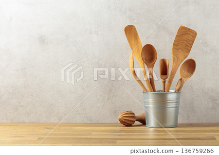 Wooden kitchen utensils in small bucket on a kitchen table. Wooden kitchen utensils in small bucket on a kitchen table. 136759266