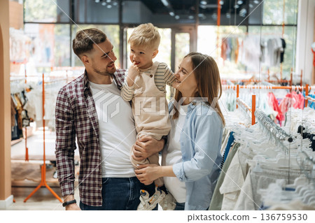Conception of love and care. Father, son and pregnant mother are in kid's clothing store 136759530