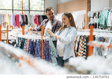 Together in the in the kid's clothing store. Pregnant woman with man Together in the in the kid's clothing store. Pregnant woman with man 136759702