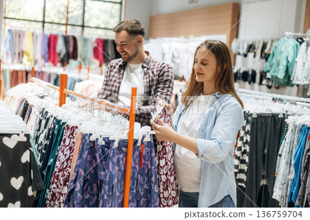 Together in the in the kid's clothing store. Pregnant woman with man Together in the in the kid's clothing store. Pregnant woman with man 136759704