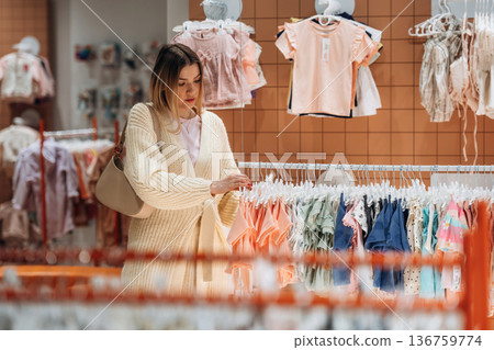 Woman is choosing wear in the kid's clothing store Woman is choosing wear in the kid's clothing store 136759774