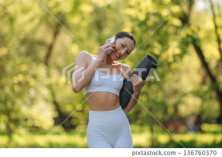 Using phone. Beautiful fitness yoga woman is outdoors, amazing nature Using phone. Beautiful fitness yoga woman is outdoors, amazing nature 136760370